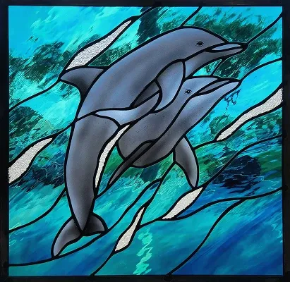 Stained glass panel of two dolphins swimming through blue and teal water