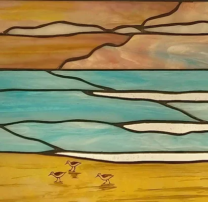 Stained glass beach scene with sandpipers on amber sand below a turquoise sea